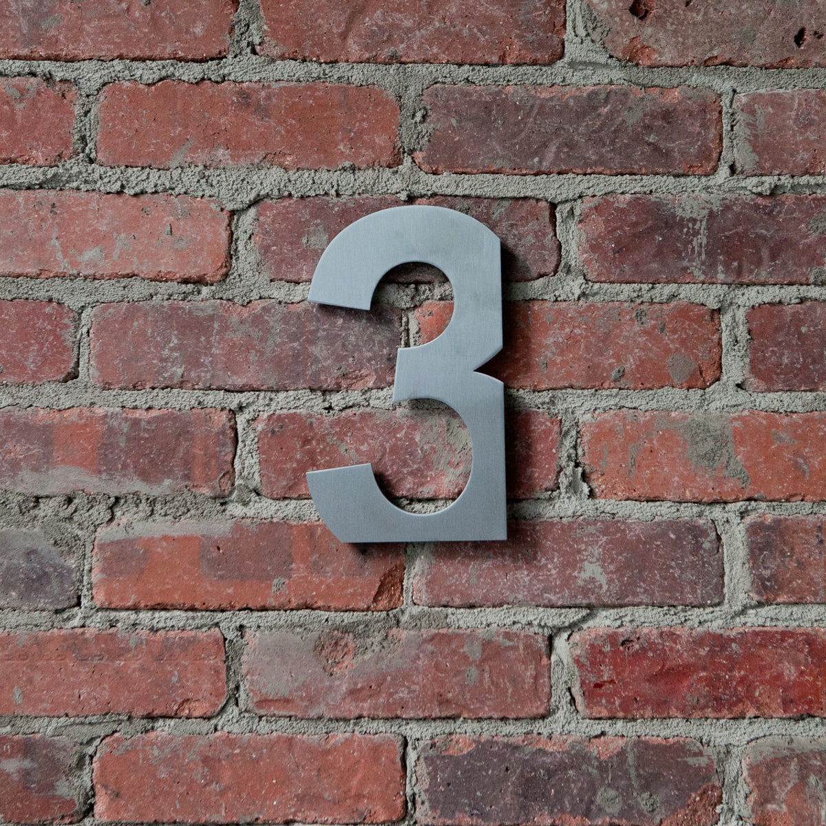 Floating modern house number on brick wall